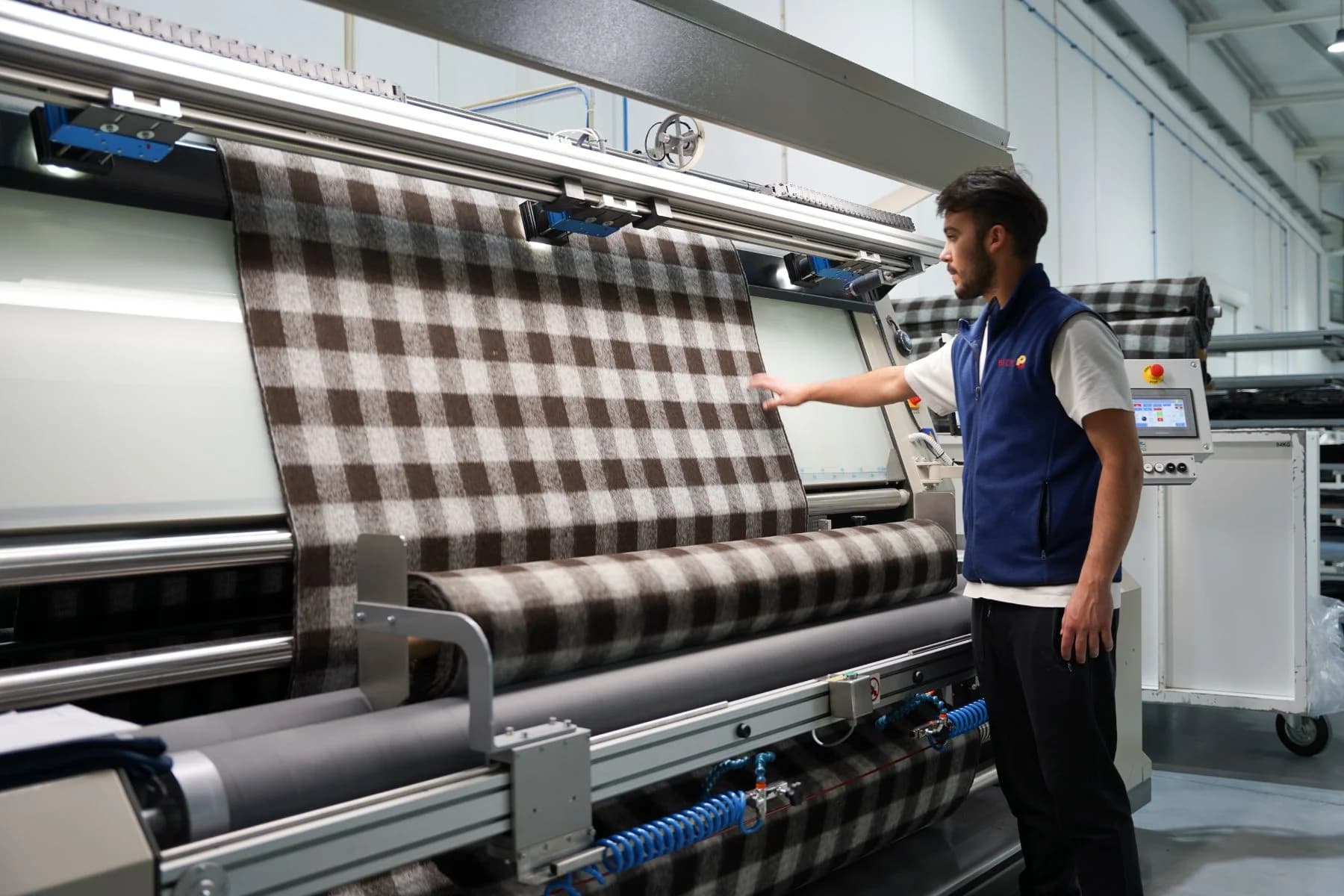 Technician inspecting checkered fabric on an automated fabric inspection machine